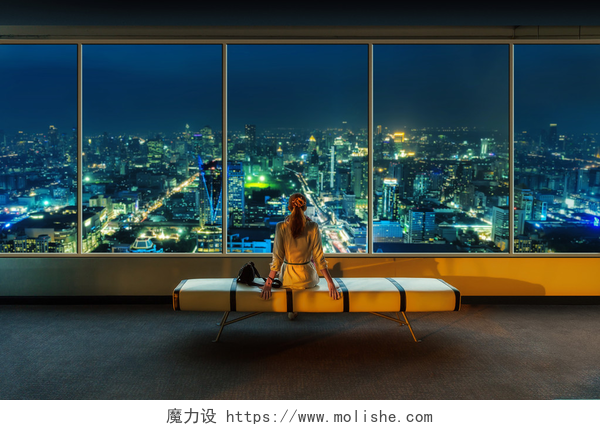 夜晚看向窗外的女人女人看着夜晚的城市景观